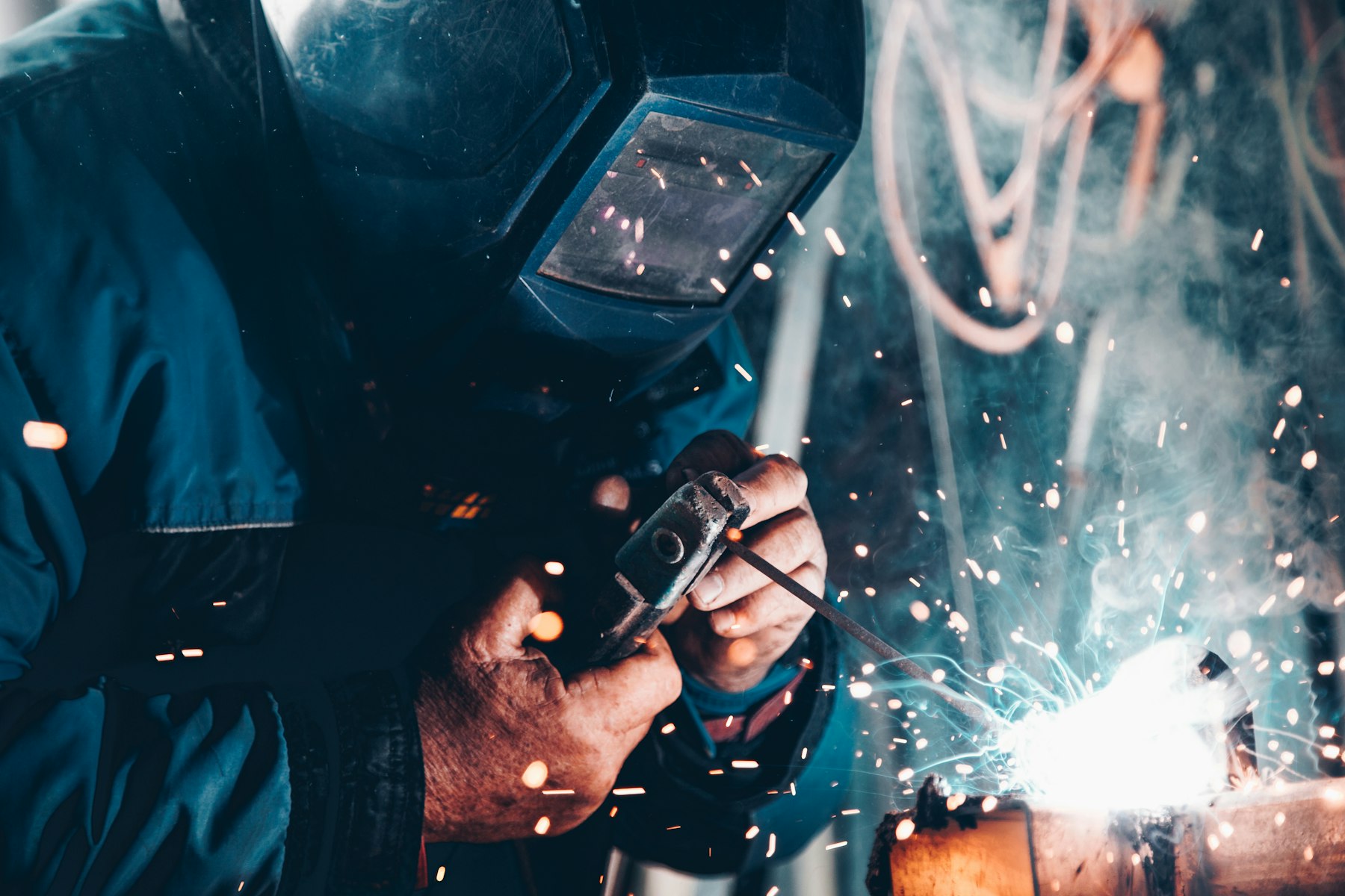 Engineer welding a metal frame with sparks flying, wearing a protective mask