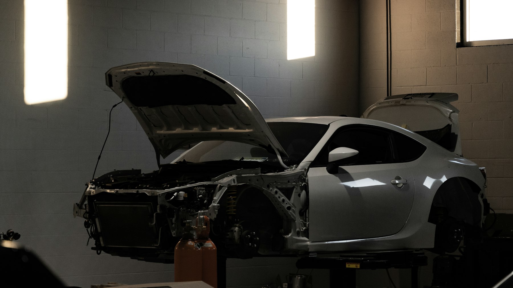 Car with hood and trunk open on a diagnostics lift in an engineering workshop